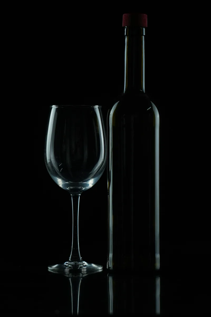 An elegant unbranded bottle and wine glass against a dark background